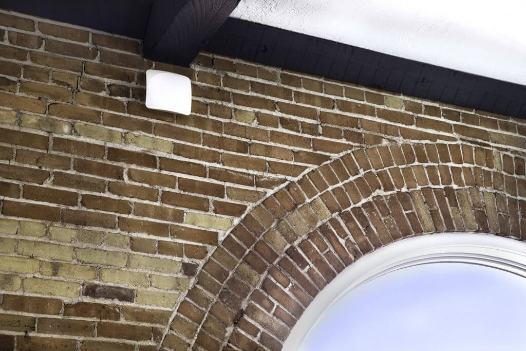 White wireless access point mounted on a brick wall