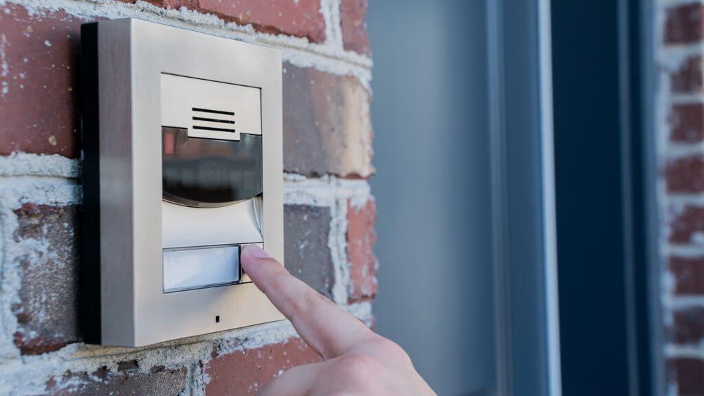 A person pressing the button on a video door station
